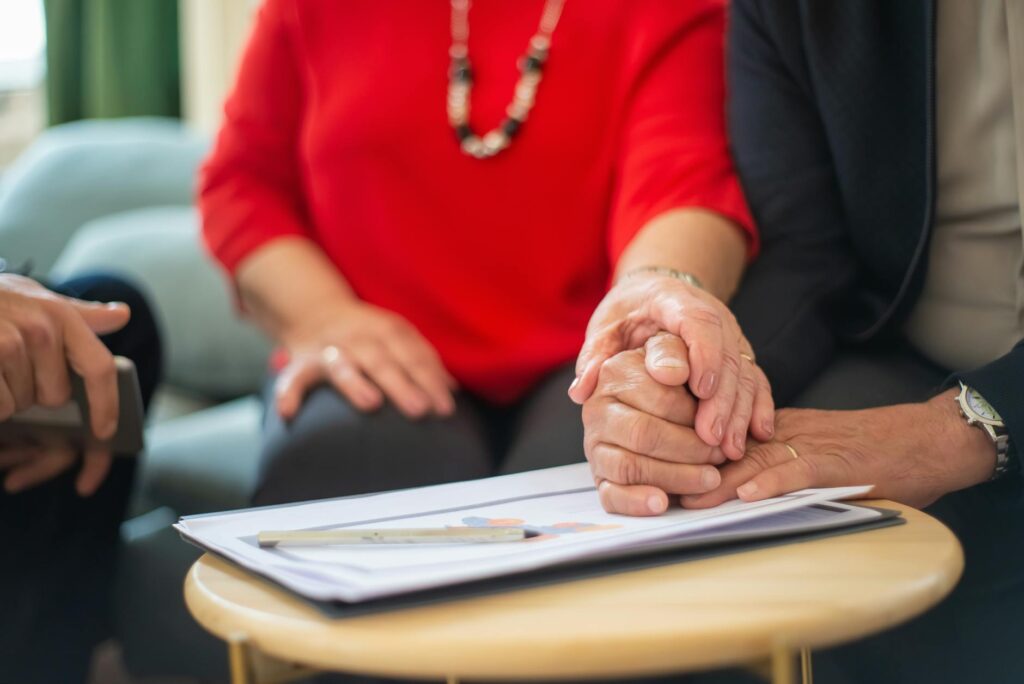 mature couple sitting in an office and holding hands on a signed document